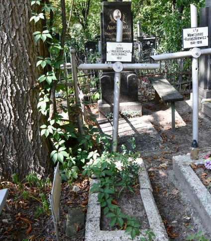 Grób oznaczony stalowym krzyżem rurkowym z metalowym kołem na przecięciu ramion. Powyżej przymocowana metalowa tabliczka z napisem. Grób ujęty opaską.