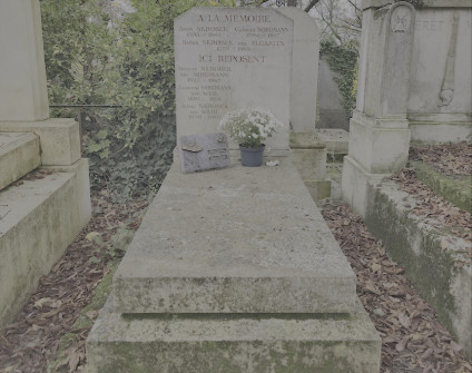 Grób rodzin Nordmannów i Skrobków z stelą na ukośnej płycie nagrobnej. Widoczne są inskrypcje na steli i poniżej. Na płycie znajduje się roślina w doniczce i mała tabliczka.