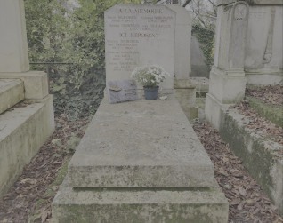 Grób rodzin Nordmannów i Skrobków z stelą na ukośnej płycie nagrobnej. Widoczne są inskrypcje na steli i poniżej. Na płycie znajduje się roślina w doniczce i mała tabliczka.