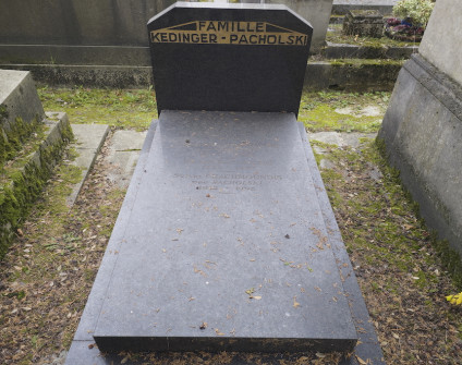 Nagrobek rodzin Kedingerów i Pacholskich z ukośną, płaską płytą oraz poziomą stelą ze ściętymi rogami. Inskrypcje wyryte na steli i płycie.