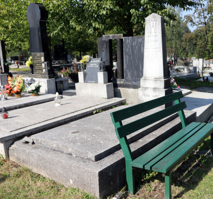 Grób Adama i Emilie Sikory z nagrobkiem w formie obelisku na dwustopniowym cokole. Pierwszy stopień z inskrypcją, obelisk zakończony krzyżem i kolejną inskrypcją. Obok znajduje się zielona ławka.