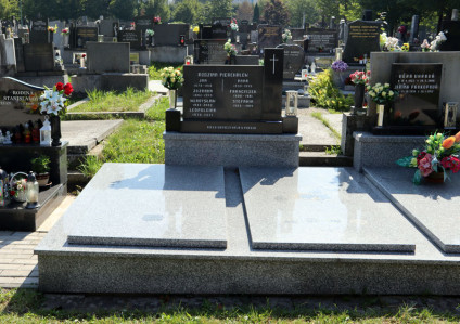 Grób rodziny Pierchałów z dwiema prostokątnymi płytami i stelą z inskrypcjami. Na bloku obok steli wyryty krzyż. W tle widoczne kwiaty i inne groby.