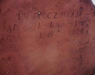 Nagrobek z krzyżem przechodzącym w pionową płytę. Krzyż ma groszkowane boki. Płyta groszkowana z tyłu i po bokach. Na froncie wyryta inskrypcja.