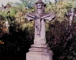 Nagrobek z krzyżem na dwustopniowym cokole. Krzyż ma zakończenia w formie trójliścia i relief Chrystusa. Cokół ma ścięte krawędzie i inskrypcję obwiedzioną żłobkiem.