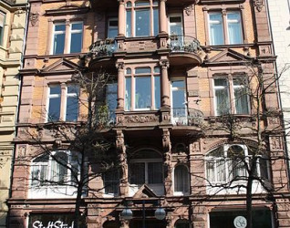 Historyczna willa zaprojektowana przez Stanisława Wojtowskiego w Bingen am Rhein, z ozdobnymi detalami architektonicznymi, dużymi łukowymi oknami i balkonem. Elewacja częściowo pokryta roślinami pnącymi.