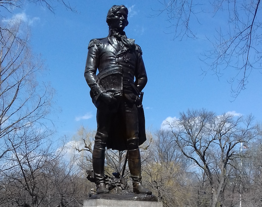 Statue en bronze de Tadeusz Kościuszko dans le Public Garden de Boston, créée par Theo Alice Ruggles Kitson en 1927. La statue se dresse sur un piédestal en granit entouré d'arbres et d'un ciel bleu clair.