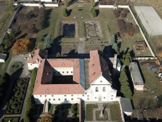 Widok z lotu ptaka na dawny klasztor Kapucynów w Olesku, ukazujący główny budynek z dziedzińcem, otoczony ogrodami i stawami. Obiekt przechodzi prace konserwatorskie.