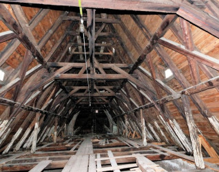 Drewniane więźby dachowe wewnątrz katedry łacińskiej we Lwowie, ukazujące historyczne techniki ciesielskie. Konstrukcja zawiera belki i podpory z widocznymi śladami starzenia.