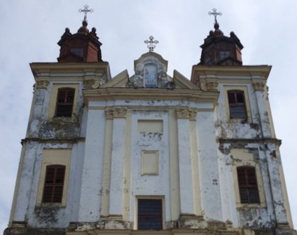 Fasada kościoła Nawiedzenia Najświętszej Maryi Panny w Bohorodczanach z dwiema wieżami, widoczne ślady zużycia i łuszcząca się farba.
