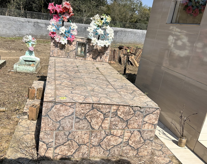 Pierre tombale de Julia et Piotr Zielinski, dont la surface ressemble à de la pierre, décorée de couronnes de fleurs artificielles colorées. Une petite photographie est incrustée dans la pierre tombale.
