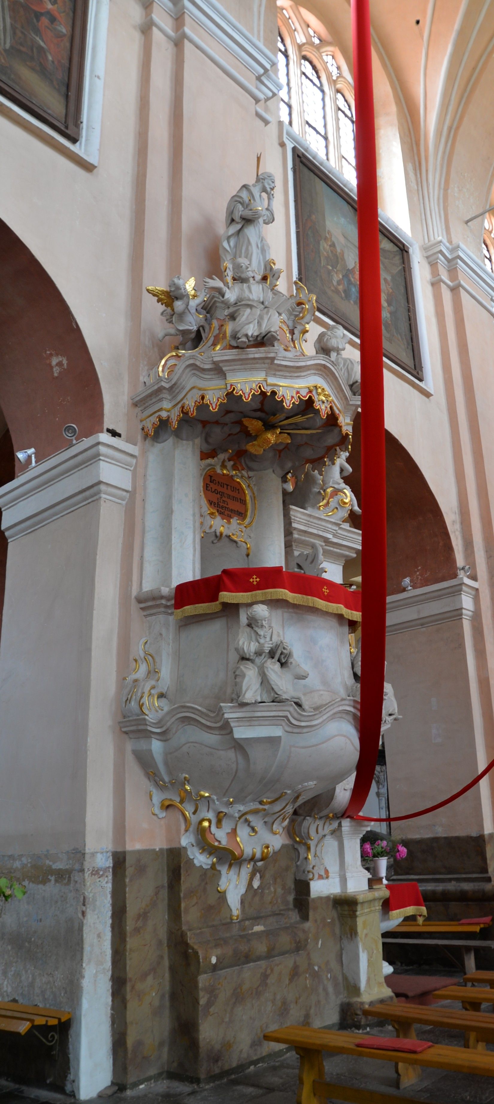 Baroque pulpit in the Bernardine church in Cytowiany, adorned with gold and red drapery, featuring angelic figures and intricate carvings.