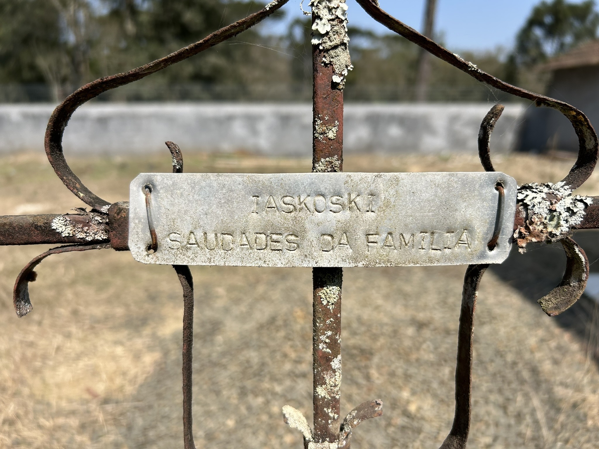 Close-up of a metal plaque on a rusty fence with the inscription 'Jaskowski Saudades da Familia'.