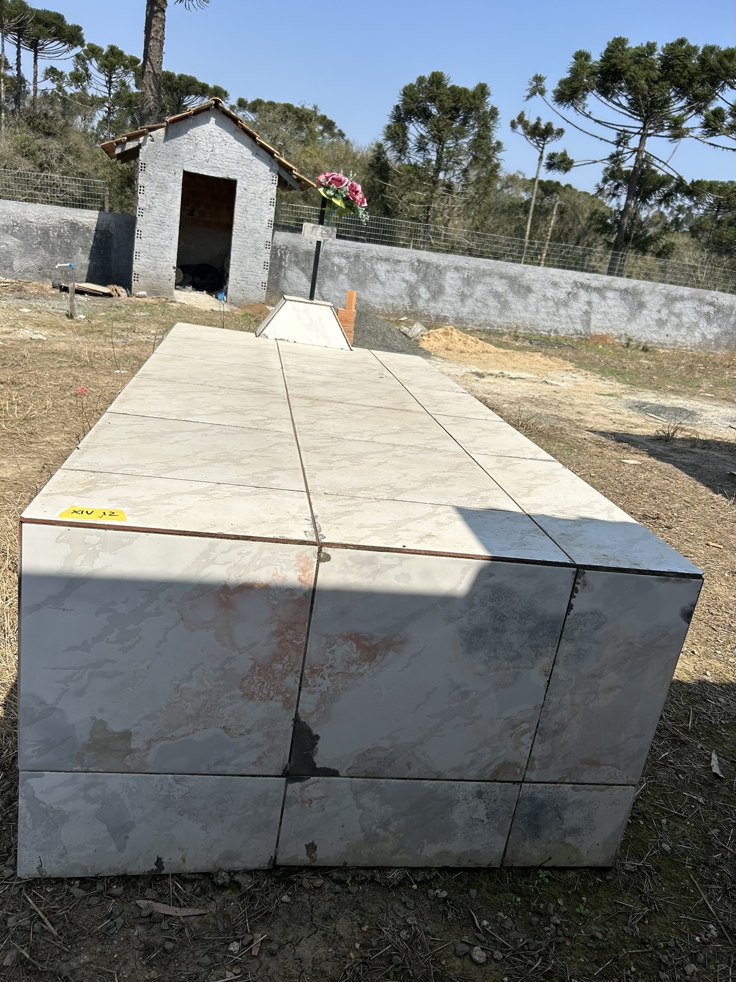 Irena Zielinski's marble tile tombstone, with a small chapel and trees surrounding the site in the background.