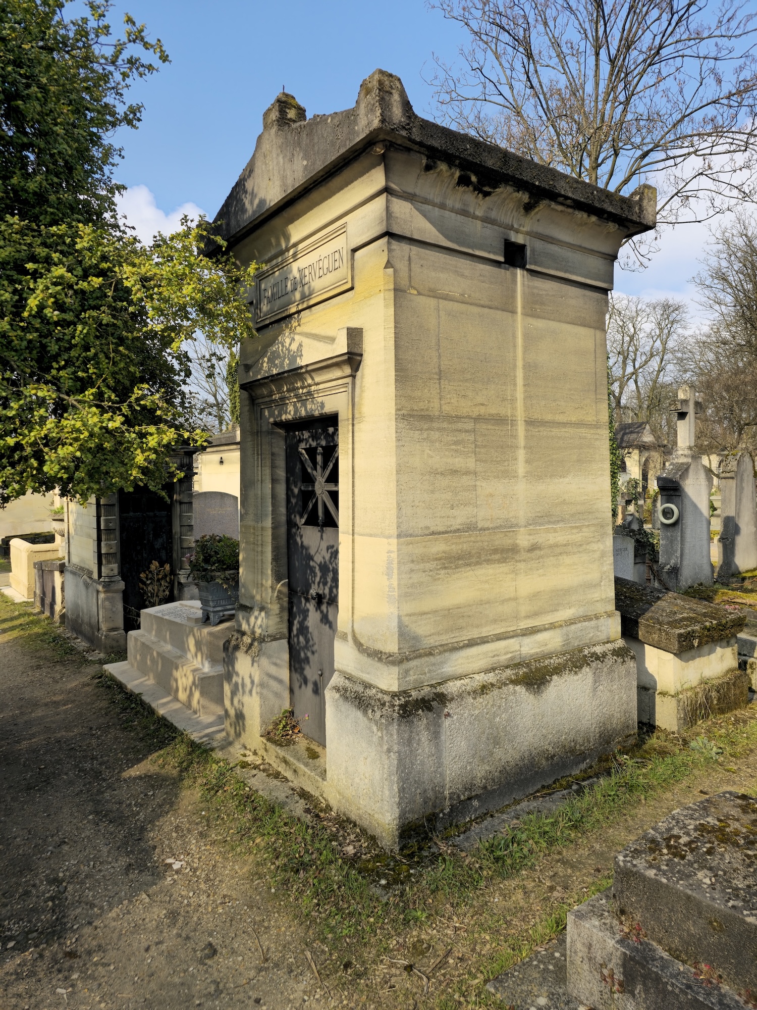 Chapel with a sarcophagus roof and a tympanum-topped entrance. Metal doors feature an openwork star motif with a cross. Inside, an altar with a cross and a stained glass window with floral motifs.