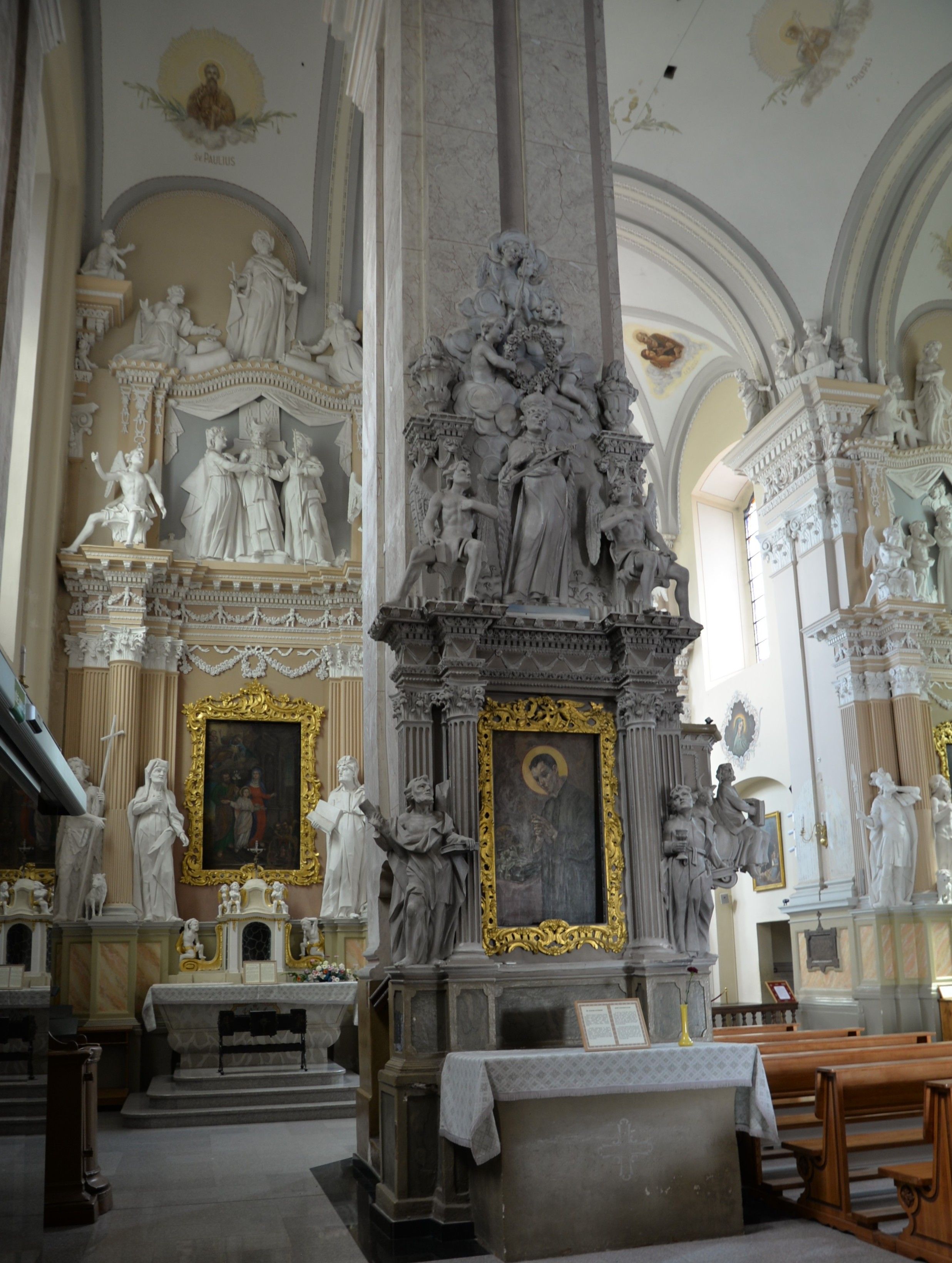 Intérieur de l'église de la Visitation de la Bienheureuse Vierge Marie à Szydłów, avec des autels ornés de statues religieuses et de peintures, y compris une image de la Vierge Marie avec un enfant dans un cadre doré.