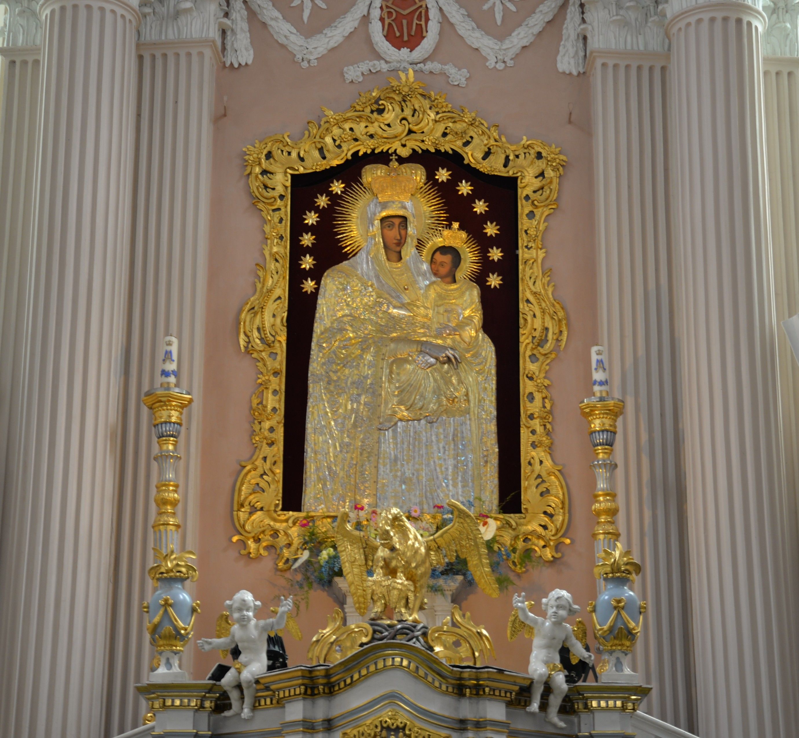 L'autel de l'église de la Visitation de la Bienheureuse Vierge Marie à Szydłów présente une icône dorée de la Vierge Marie avec l'Enfant, entourée de décorations ornées et flanquée de colonnes.