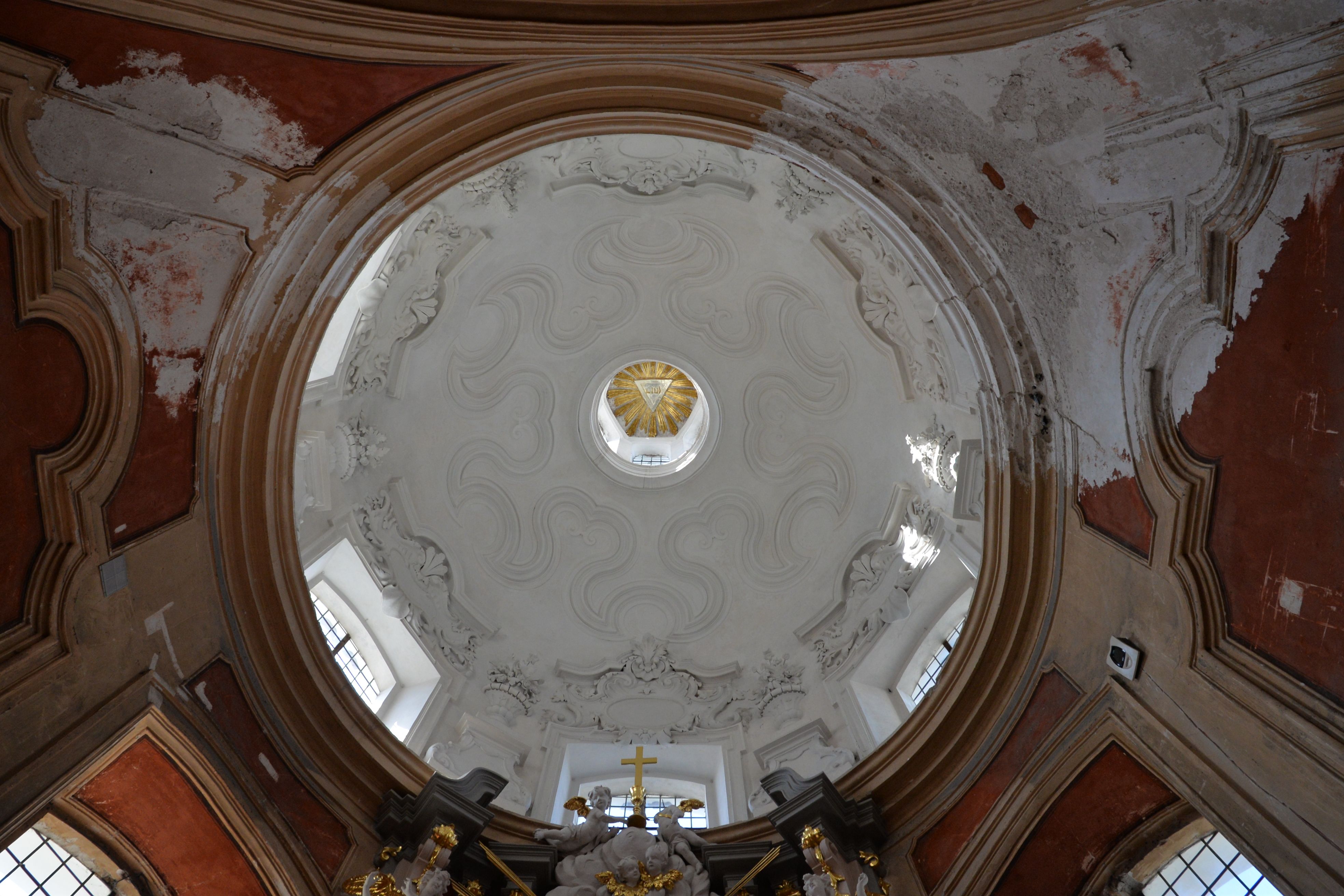 Interior view of the dome of the Benedictine Church of St. Catherine in Vilnius, featuring intricate stucco decorations and a central oculus with golden elements.