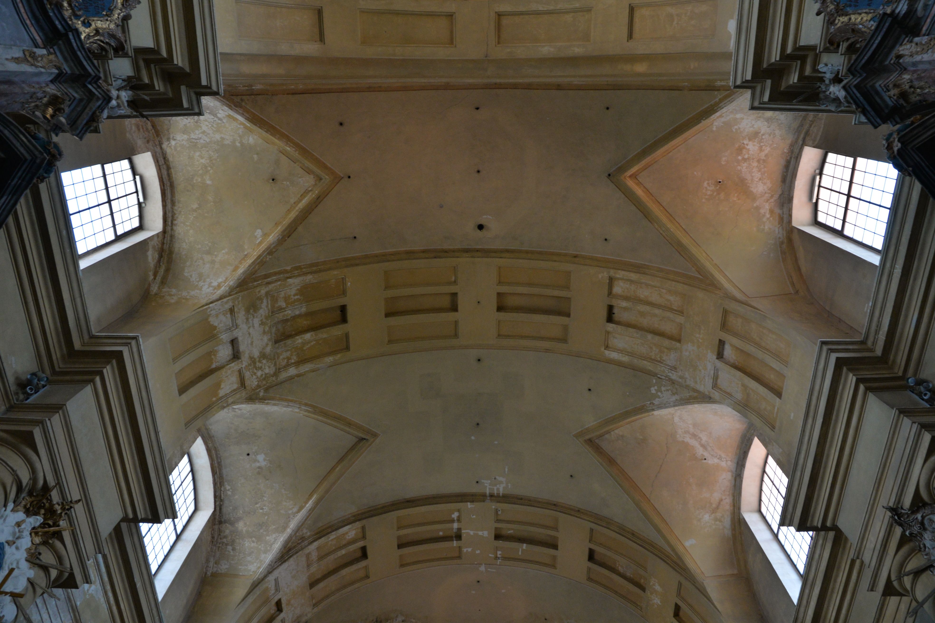 Ceiling of the Church of St. Catherine in Vilnius, showing a barrel vault with lunettes and decorative stucco elements. The structure includes Tuscan columns and large windows.