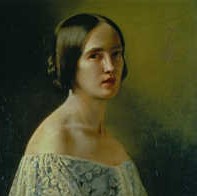 Portrait of a woman with dark hair, wearing an off-the-shoulder lace dress, set against a dark background.