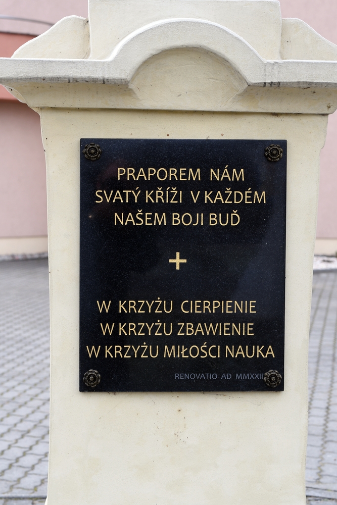 Plaque on a roadside cross in Těšín Silesia, Czech side, with inscriptions in Czech and Polish: 'Praporem nám svatý kříži v každém našem boji buď' and 'In the cross suffering, in the cross salvation, in the cross love learning'.