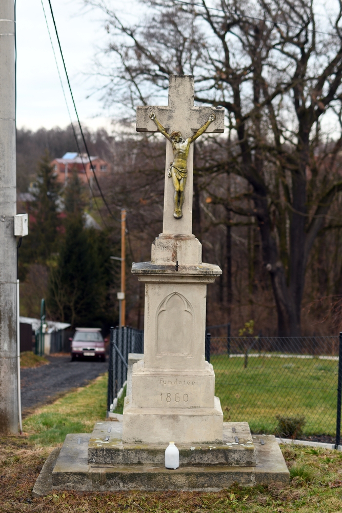 Roadside cross from 1860 with a statue of Christ, located in the countryside of Těšín Silesia on the Czech side. The cross stands on a stone plinth with the inscription 'Founder 1860'.