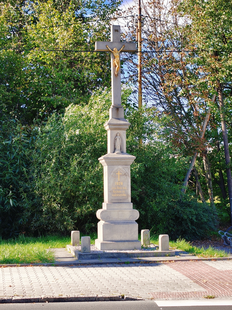 Roadside cross against a green background with stone base and gold Christ figure. Inscription: 'Jesus my God, I love you above all things 1920'.
