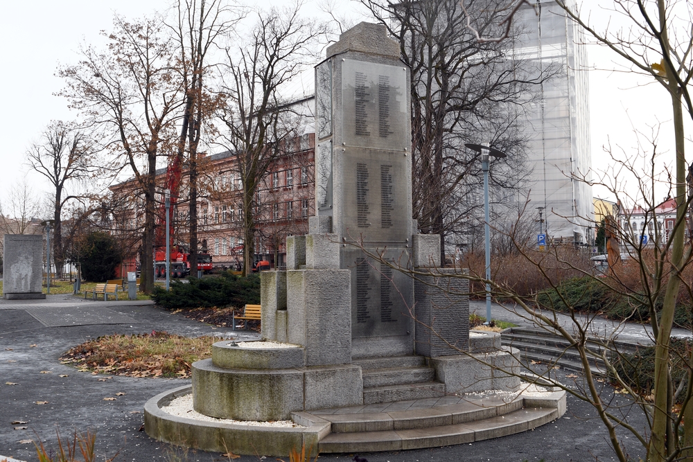 Пам'ятник жертвам Першої світової війни в Карвіні, Чехія, з кам'яним монументом з вигравіруваними іменами, оточений деревами та лавками в парку.