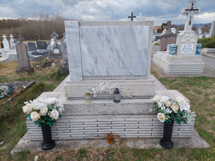 Grób polskiego uchodźcy Franciszka Miegucia i żołnierza sowieckiego na cmentarzu w Dejtar. Grób z jasną płytą kamienną z węgierską inskrypcją, otoczony białymi kwiatami i świecami.