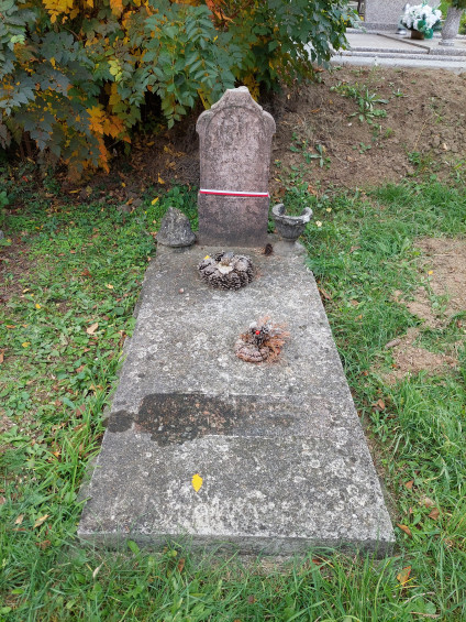 Grób polskiego żołnierza Piotra Kani na cmentarzu w Lábatlan. Kamienny nagrobek z inskrypcjami w języku polskim i węgierskim. Na poziomej płycie leży mały wieniec, otoczony trawą i drzewami.