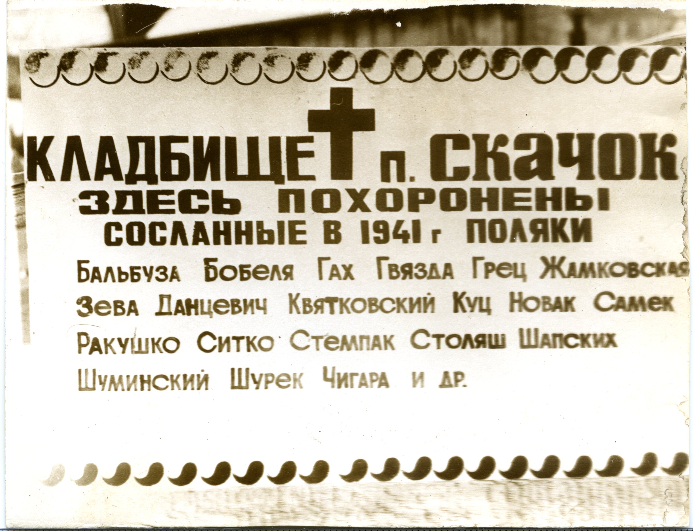 Меморіальна дошка з російським написом на кладовищі в Скачку, з переліком імен поляків, висланих у 1941 році, включаючи Бальбуза, Бобеля, Гах, Гв'язда, Грец, Жамковська, Зева, Данцевич, Квятковський, Куц, Новак, Самек, Ракушко, Сітко, Стемпак, Столяш, Шапських, Шумінський, Шурек, Чігара.