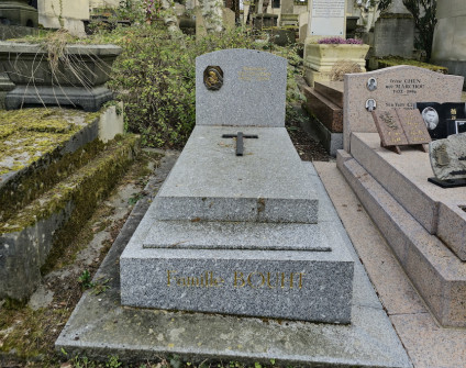 Nagrobek rodziny Bouth i Stanisława Szczeszka. Płaska, lekko skośna płyta z czarnym krzyżem. Niski postument z ćwierćłukowym szczytem zawiera metalowy relief Matki Boskiej z dzieciątkiem. Obecne są inskrypcje.