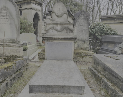 Nagrobek z cokołem schodkowym i skośną płytą, motyw antyczny z girlandą podtrzymywaną przez czaszki byków. Inskrypcja na czarnej marmurowej tablicy. Otaczające nagrobki i zieleń.