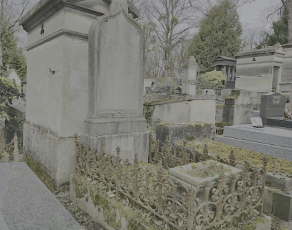 Nagrobek rodzin Drouet i Romańskich z gotyckim łukiem i krzyżem, otoczony żeliwnym ogrodzeniem z motywami pochodni i makówek, znajdujący się na cmentarzu.