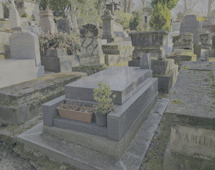 Nagrobek Jakuba Bartoszyka z wysokim cokołem i skośną płaską płytą z kamiennym wazonem z inicjałami 'JB'. Na prawym boku płyty widoczna inskrypcja.