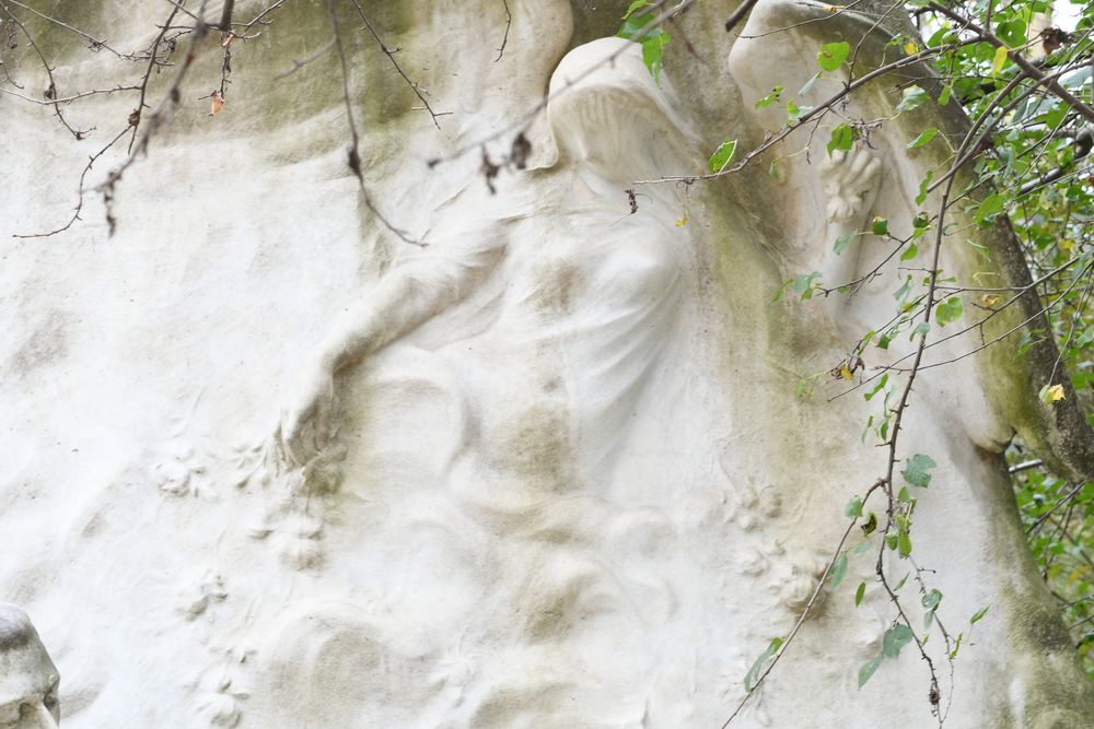 Detail of the Chopin monument in Park Monceau, Paris, showing a sculpted figure of a winged Muse scattering flowers, symbolising inspiration and sound.