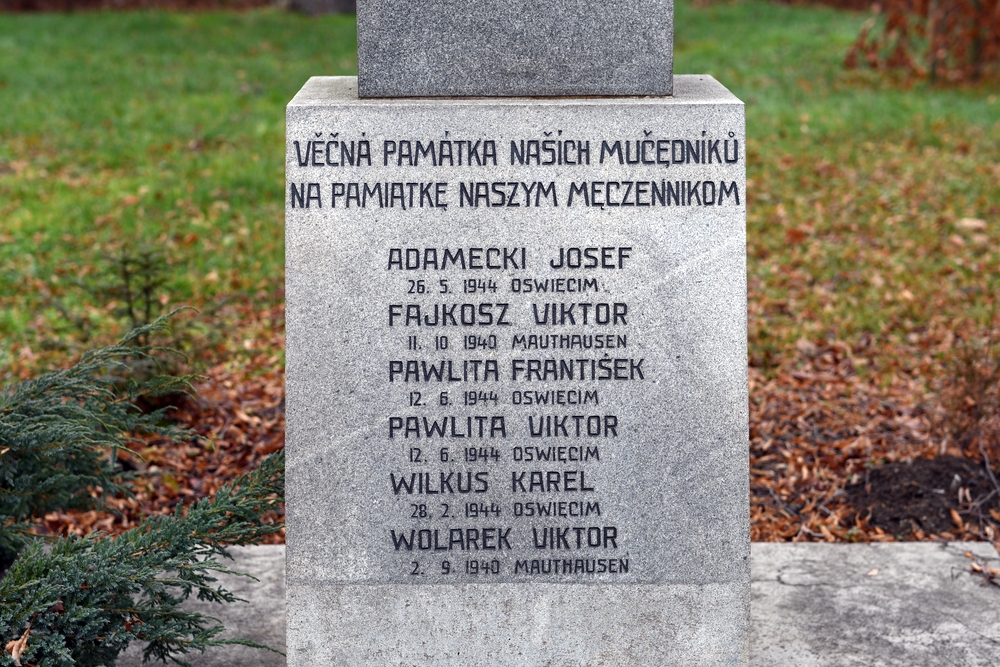 Кам'яний пам'ятник у Петровицях біля Карвіни, що вшановує жертв Другої світової війни, з написами чеською та польською мовами, які перераховують імена та дати смерті в Аушвіці та Маутгаузені.