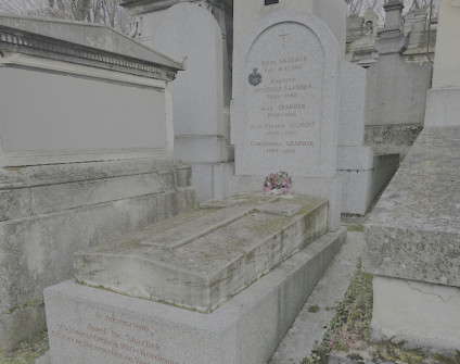 Nagrobek rodziny Skarbków i Poullierów, Jeanne Brousse i Jean-Pierre’a Dorgeta. Zawiera schodkowy cokół, pionową stelę z inskrypcjami i brązowy herb. Kwiaty u podstawy.