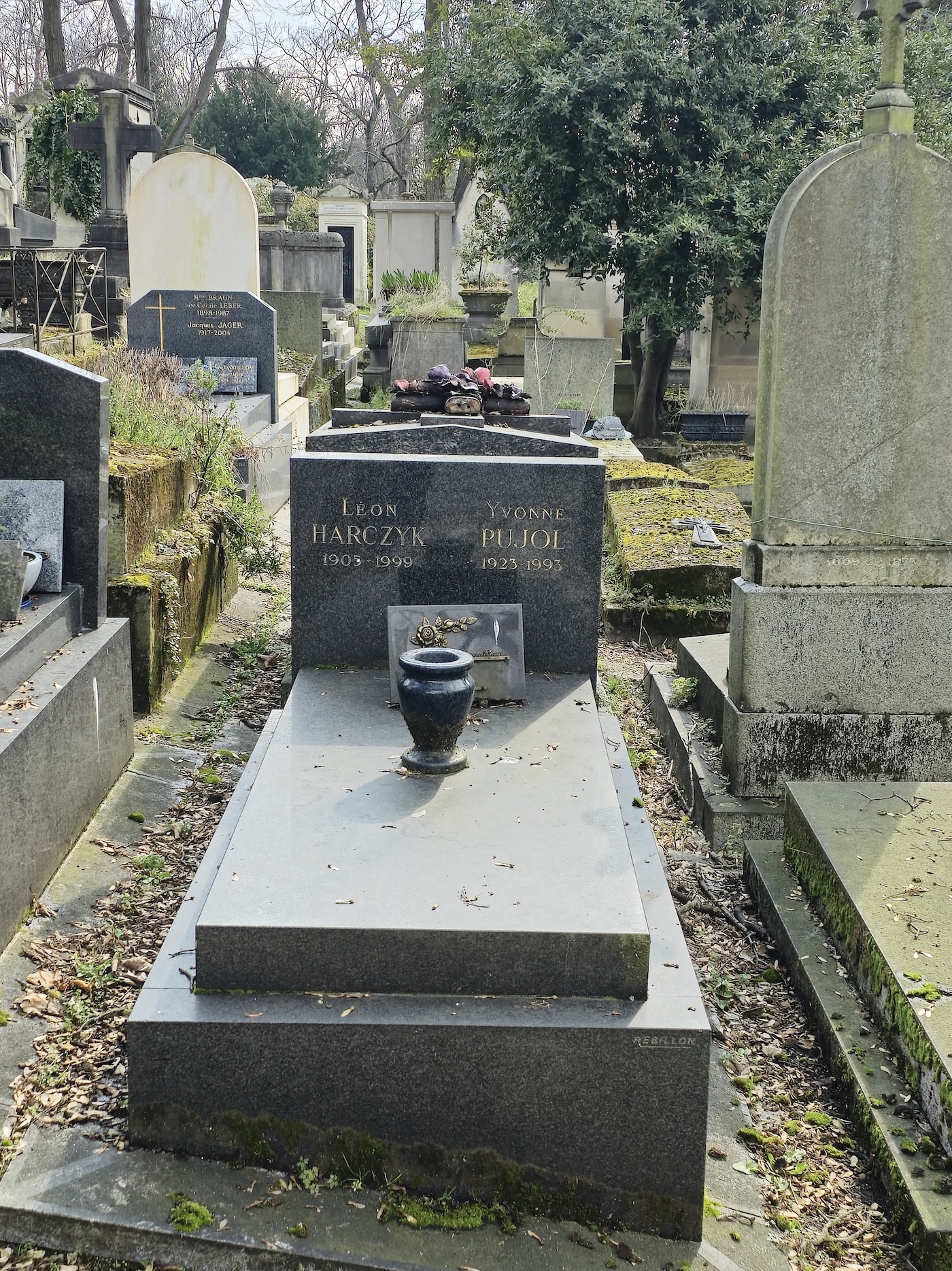 Gravestone of Leon Harczyk and Yvonne Pujol with inscriptions on a rectangular stele. A granite plaque with a sunflower motif is placed on the slab.