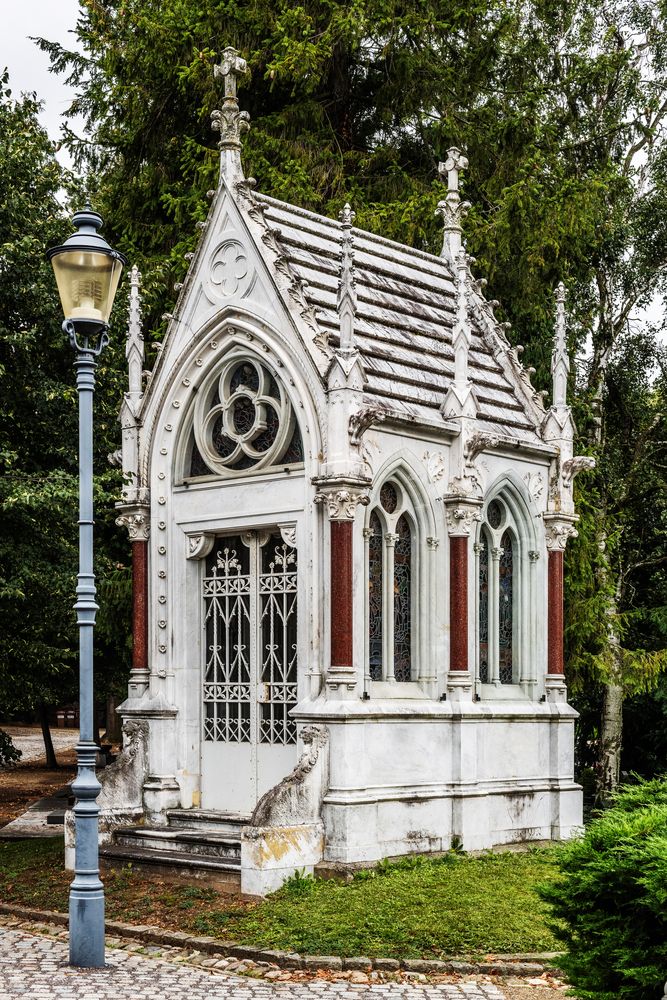 The Grauer family chapel in Opava, a neo-Gothic mausoleum with pointed arches and decorative pinnacles, surrounded by trees and a lantern.