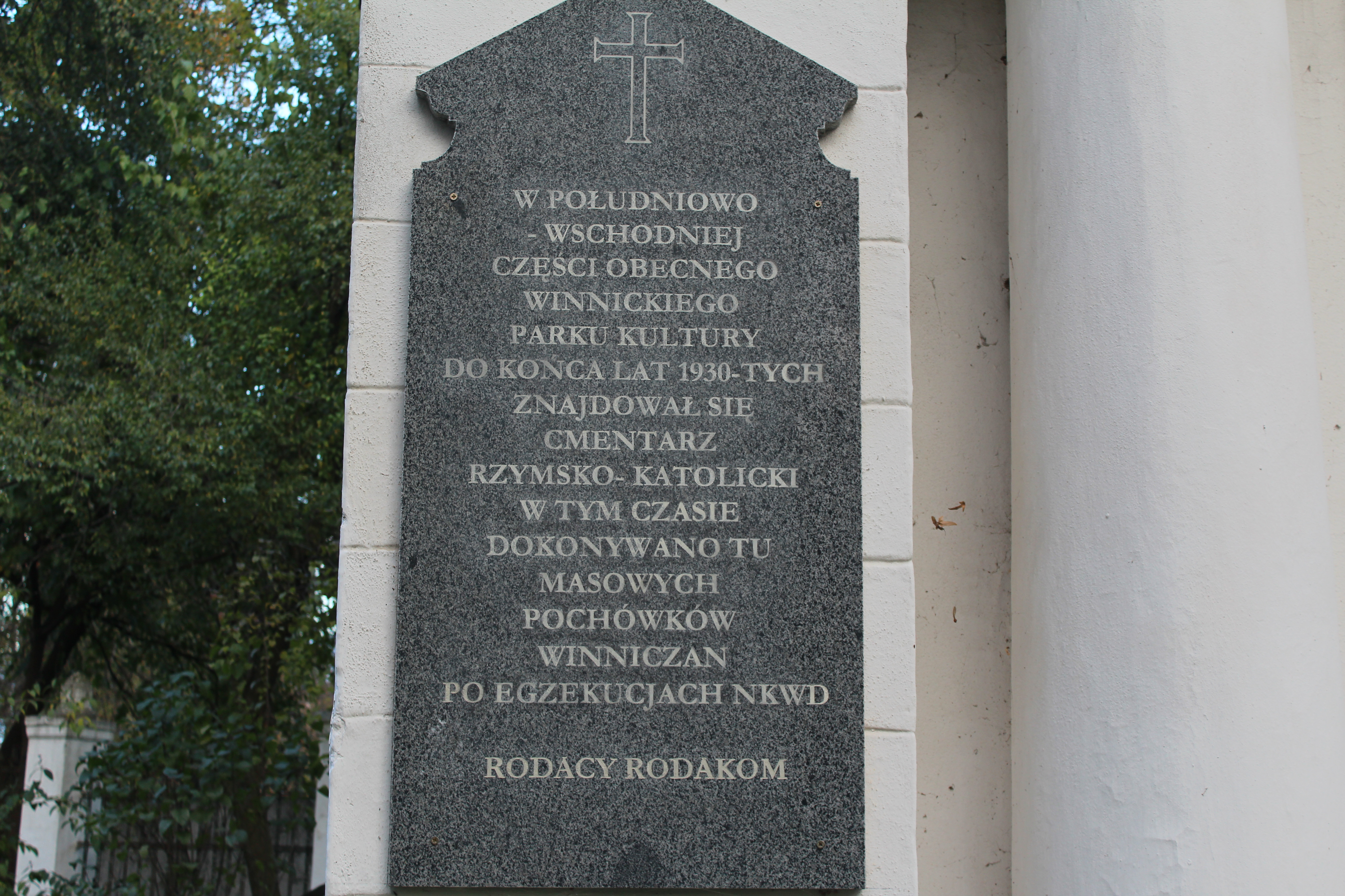 Plaque sur un mur de chapelle dans le parc central de Vinnytsia commémorant les exécutions de Polonais par le NKVD dans les années 1930. Inscription en polonais avec une croix en haut.