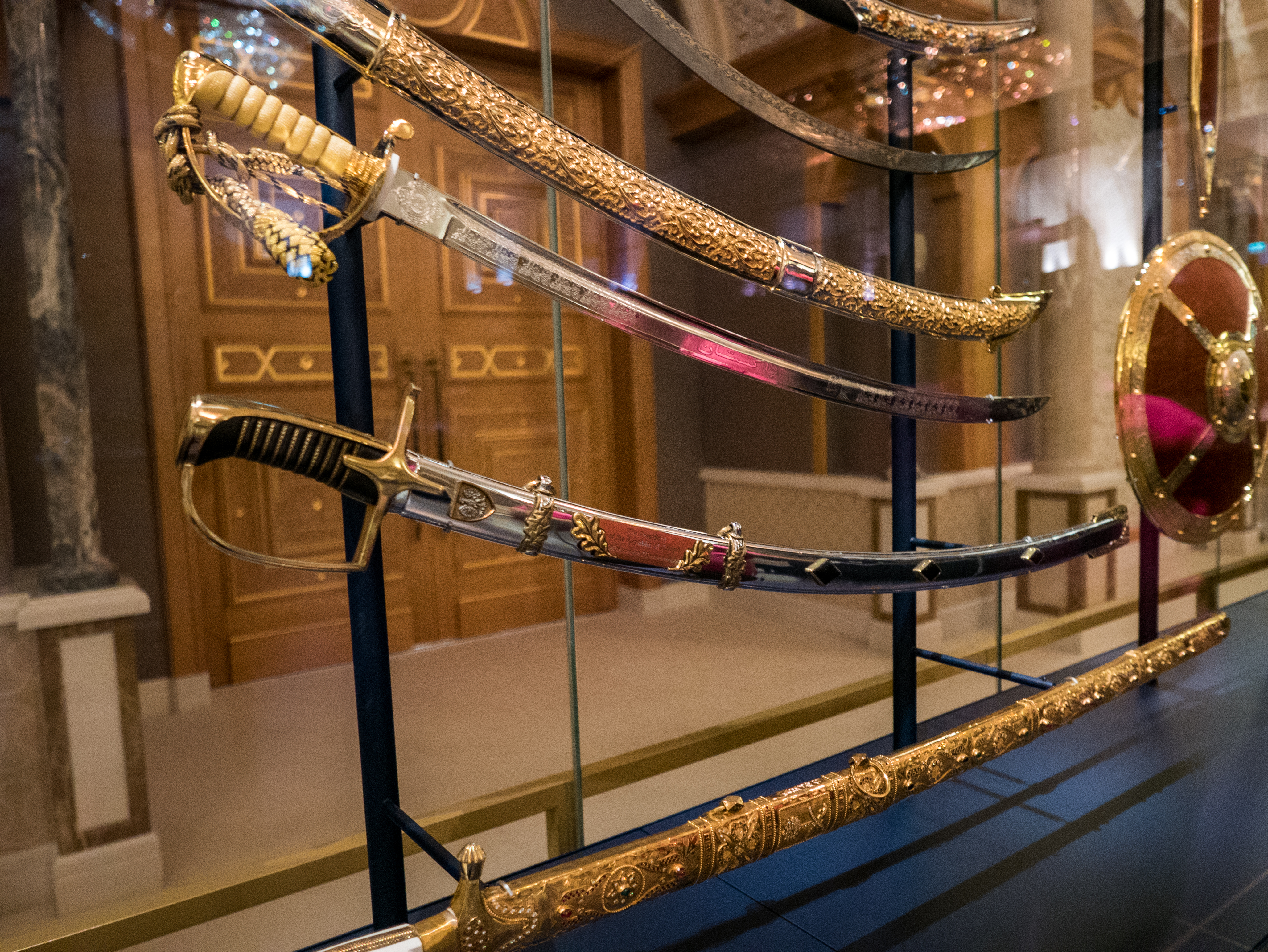 A display of ornate swords, including a saber presented by President Aleksander Kwaśniewski, in a glass case at the Presidential Palace in Abu Dhabi.