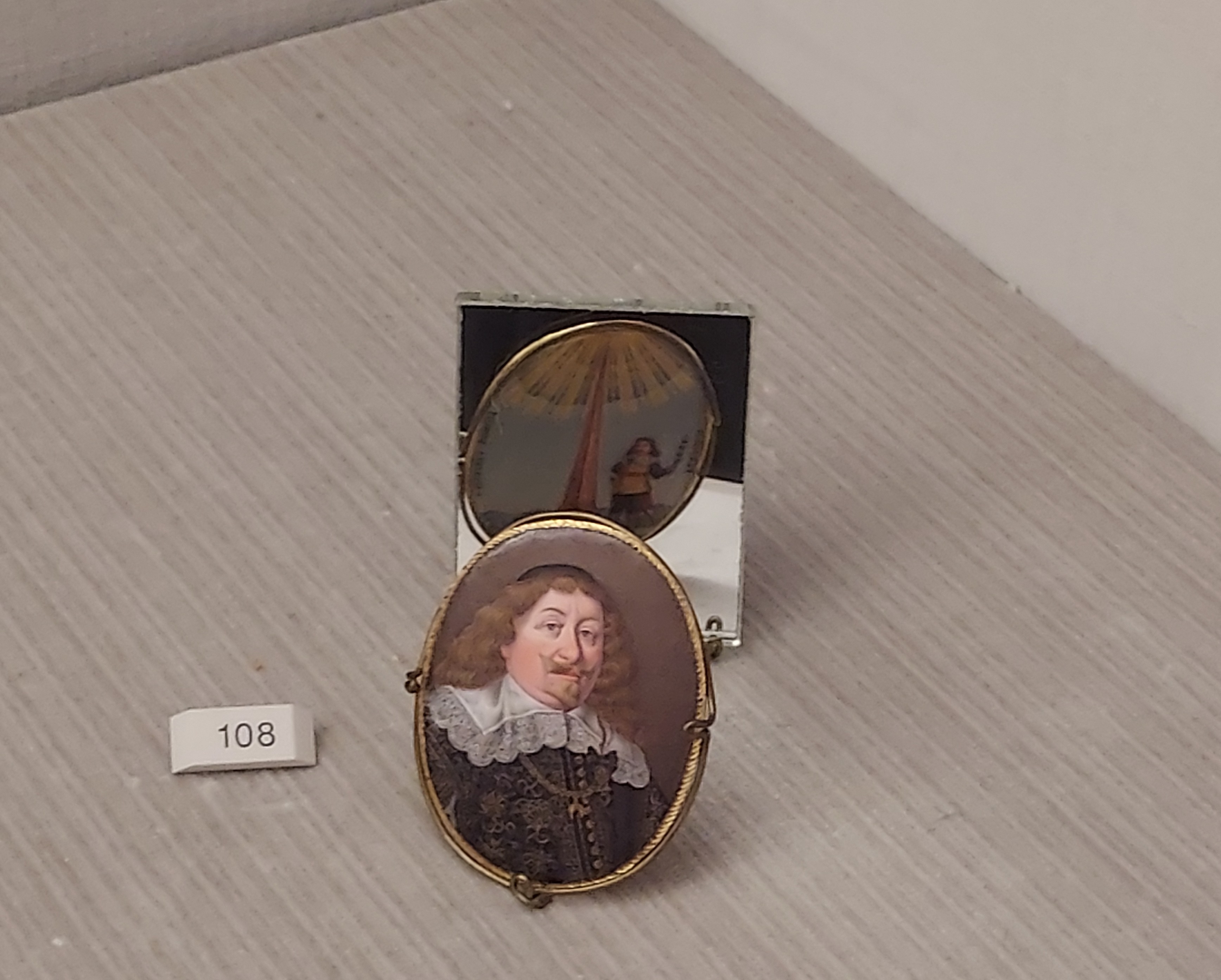 Miniature of King Władysław IV Vasa by Paul Prieur, 1645, in Gemäldegalerie, Berlin. The oval portrait shows the king in ornate attire with the Order of the Golden Fleece chain and a purple headpiece. Displayed on a light surface with a label '108'.