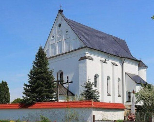 The Church of the Holy Trinity in Chernavchytsya, Belarus, features a white plastered facade with a high gable and arched windows. A red brick fence and trees are in the foreground.