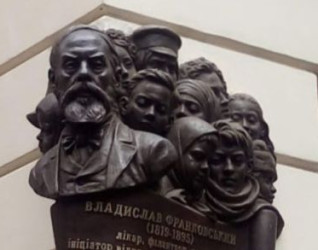 Tablica pamiątkowa na budynku w Charkowie z reliefowym popiersiem brodatego mężczyzny w otoczeniu grupy dzieci oraz napisem w języku ukraińskim