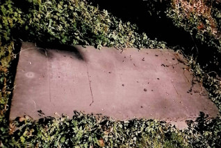 Nagrobek Katarzyny Berezy z wyrytym krzyżem i inskrypcją obwiedzioną ramką o zaokrąglonych narożach, otoczony trawą.