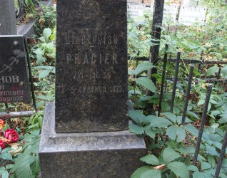 Nagrobek Mieczysława Pragiera z wyrytą inskrypcją, otoczony zielenią i metalowym ogrodzeniem. W pobliżu inne nagrobki we wspólnej kwaterze.