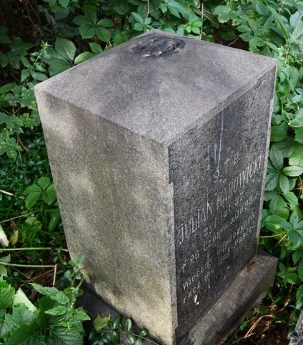 Nagrobek Juliana Radowickiego z niezachowanym krzyżem na cokole i podstawie. Podstawa i cokół mają ścięte górne krawędzie. Na przedniej płycinie z uszakami wyryta inskrypcja.