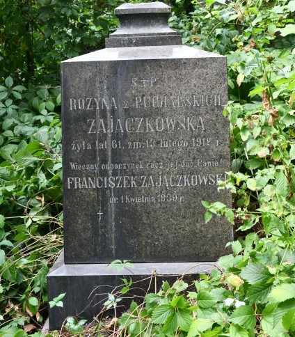 Nagrobek Franciszka i Rozyny Zajączkowskich z wyrytym napisem, otoczony zielenią.