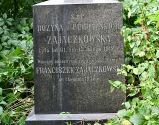 Nagrobek Franciszka i Rozyny Zajączkowskich z wyrytym napisem, otoczony zielenią.