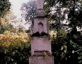 Nagrobek Magdaleny i Franciszka Białkowskich z krzyżem na trójstopniowym cokole otoczony drzewami.